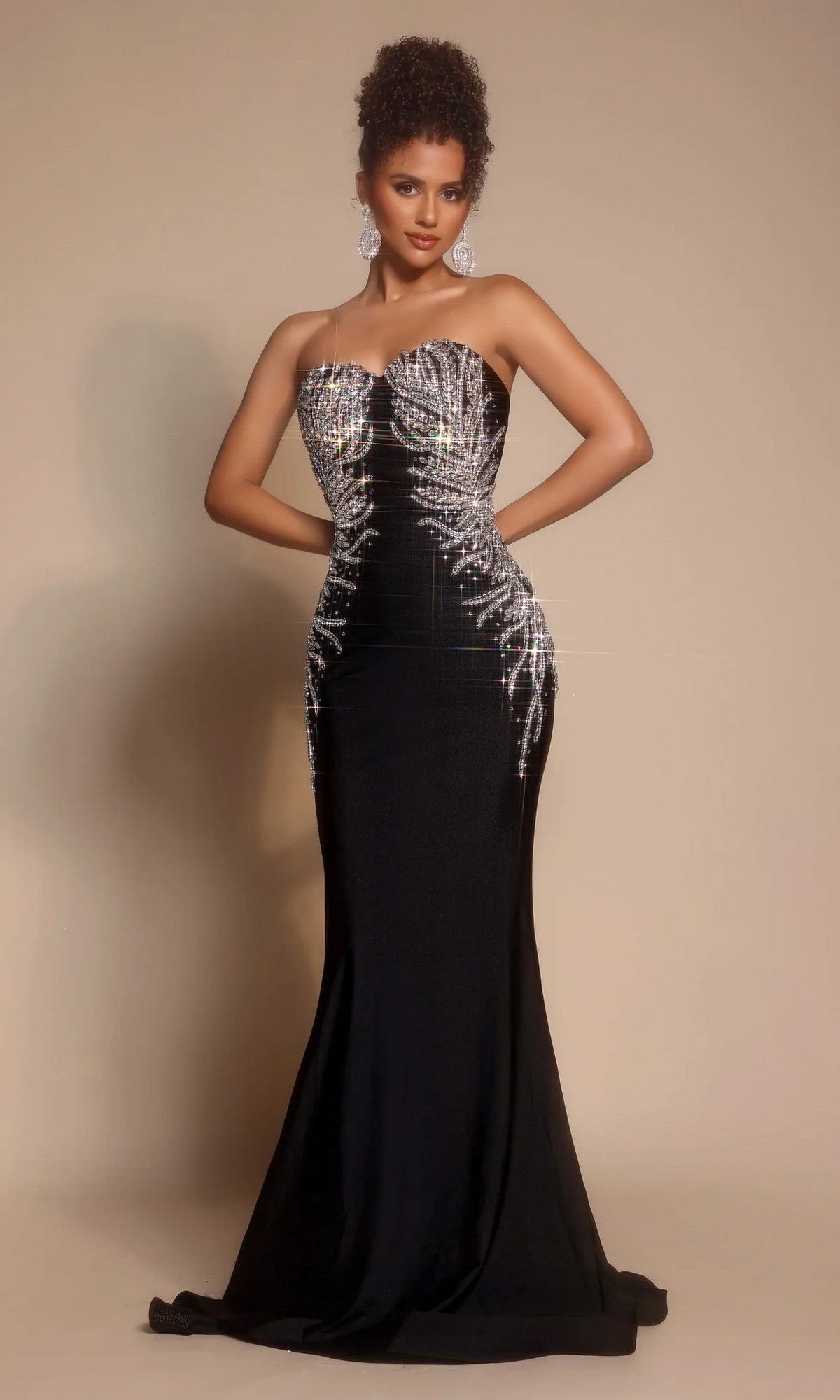 A woman poses in the black Portia and Scarlett PS26331E long formal dress with a strapless sweetheart neckline, silver sequin embellishments, and statement earrings against a neutral background.